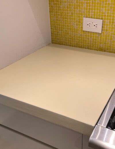 image shows a light-colored kitchen countertop with a stainless steel stove to the right