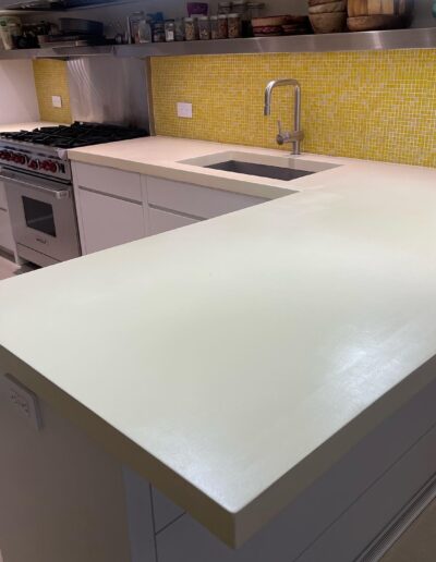 image of a kitchen with light-colored countertops and a yellow tile backsplash