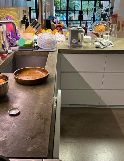 image shows a messy kitchen counter with dirty dishes, a sink, and various kitchen utensils and appliances