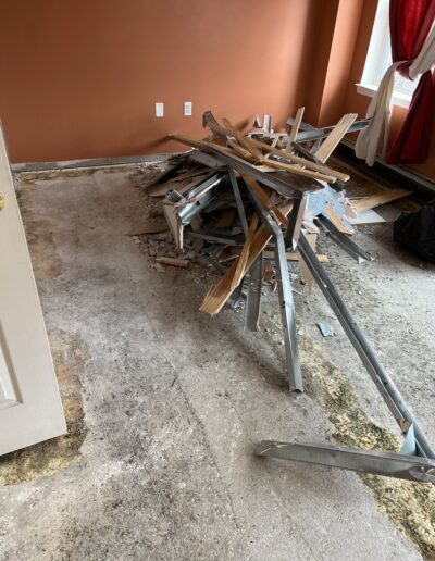 image shows a room with a pile of construction debris on the floor, including wood and metal pieces