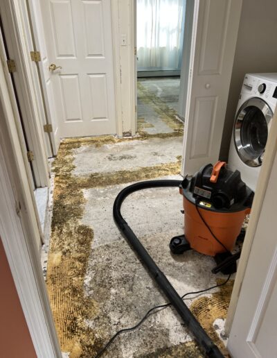 image shows a Ridgid wet/dry shop vacuum sitting in a hallway with a partially ripped up floor