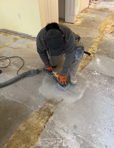 worker is using a floor sander on a concrete floor