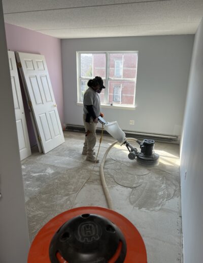 A person operating a floor sanding machine in a room